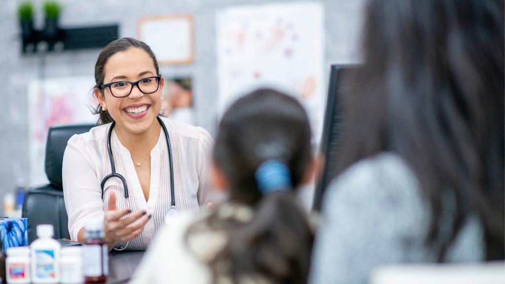Pediatrician talking to girl and her parent.